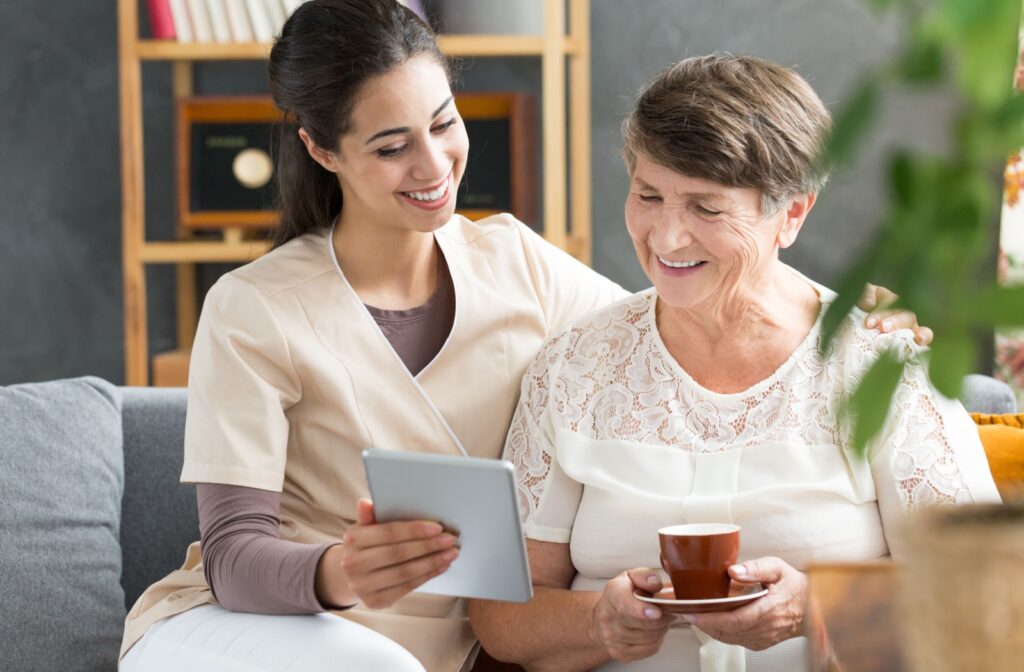 An assisted living caregiver sits with a resident and discusses diabetes management using a tablet.