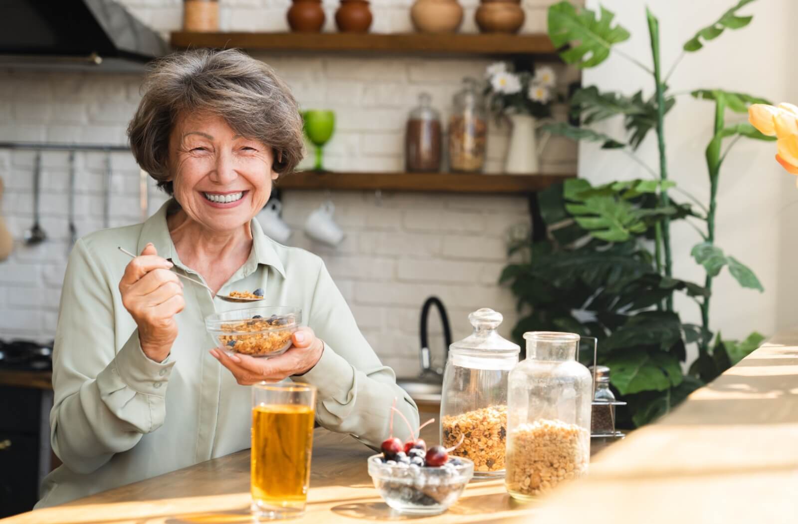 A senior smiles as they have their breakfast of oats and fruit, a meal stocked full of fiber to promote healthy digestion